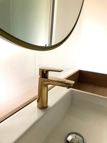 a bathroom sink with a gold faucet and a mirror at Hotel Starkl - Heritage & Unique in Bled