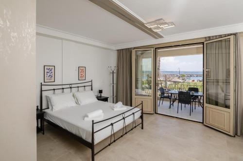 a bedroom with a bed and a balcony with a table at Light of Faros apartments in Petalidi