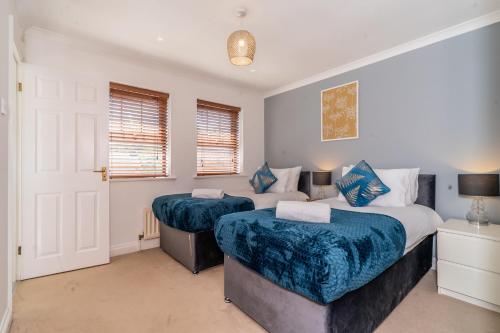 a bedroom with two beds and two windows at MK City Center House, perfect for FAMILIES, GROUPS, free parking, Sky TV, Desk space managed by CHIQUE PROPERTIES LTD in Milton Keynes