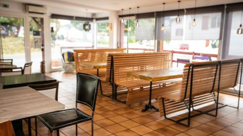 a restaurant with wooden tables and chairs and windows at Hotel Restaurant Bonnet in Saint-Pée-sur-Nivelle