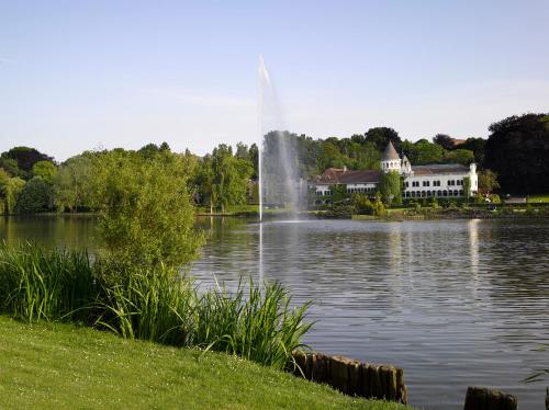 a fountain in the middle of a lake with a building at Martin's Château Du Lac in Genval