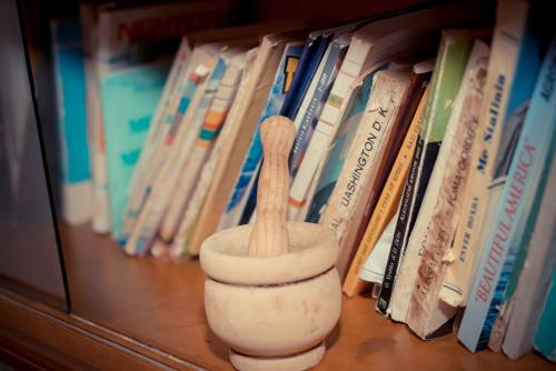 a book shelf with a wooden vase in front of books at The Fir Gate in Gjirokastër