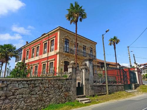 une maison ancienne avec un mur en pierre et des palmiers dans l'établissement La Venta de Miyares - Casa de Indianos, à Piloña