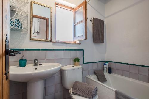 a bathroom with a sink and a toilet and a mirror at Casa Sol - traditional village house with pool and view in Pinos del Valle