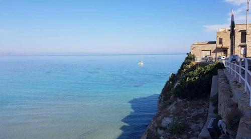 a building on a cliff next to the ocean at By the Sea in Terrasini