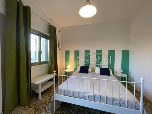 una camera da letto con letto a righe verdi e bianche di casa in spiaggia a Marina di Pescoluse