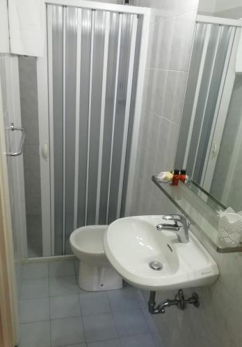 a white bathroom with a sink and a shower at La locanda di Gioele in Lido di Camaiore