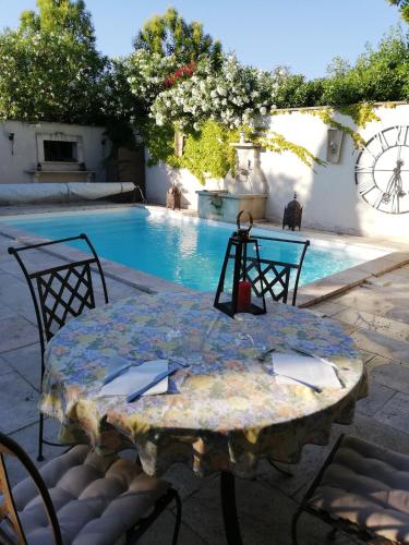 a table and chairs in front of a swimming pool at Calenco des Carlenes in Tarascon