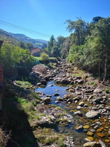 a river with rocks and trees on a hill at Posada Rural Peñasagra in Quintanilla