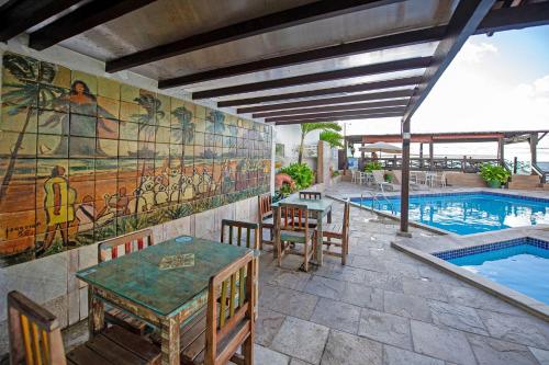 a patio with a table and chairs next to a swimming pool at Hotel Costeiro in Olinda