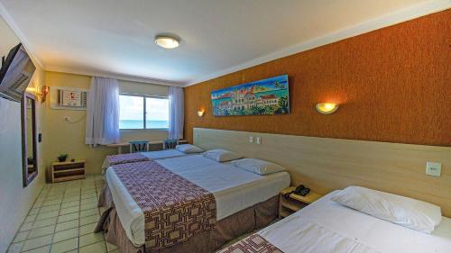 a hotel room with two beds and a window at Hotel Costeiro in Olinda