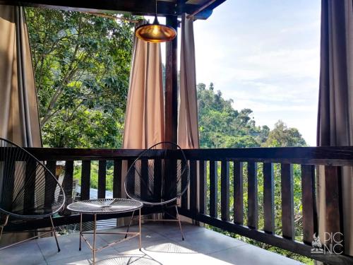 a balcony with chairs and a large window at EL PICNIC ATITLÁN in Tzununá