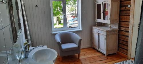 Aadelheide Family Apartments في بارنو: حمام فيه كرسي ومغسلة ونافذة