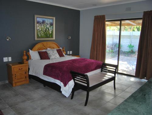 a bedroom with a bed and a chair and a window at 14 Cluster Cottages in George