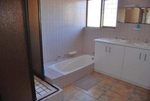 a bathroom with a bath tub and two sinks at 14 Cluster Cottages in George