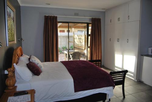 a bedroom with a large bed and a balcony at 14 Cluster Cottages in George
