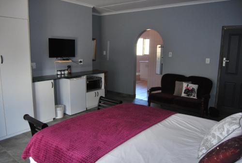 a bedroom with a bed with a pink blanket on it at 14 Cluster Cottages in George