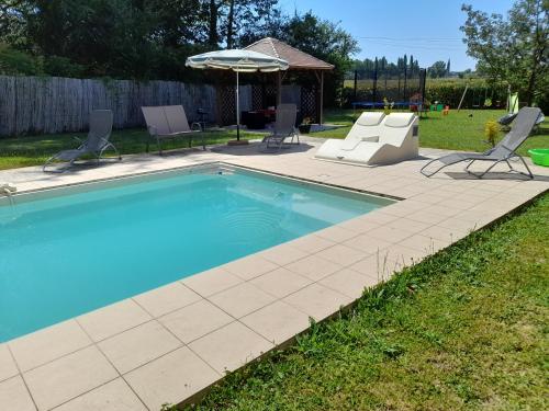 una piscina en un patio con sillas y sombrilla en L'oasis, en Mouleydier