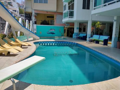 a swimming pool with a slide in a building at Suites Angelopolis in Acapulco