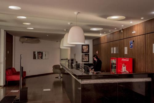 a woman sitting at a counter in a lobby at Fenix Hotel Araxá in Araxá