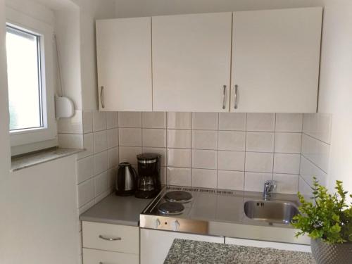 a kitchen with white cabinets and a sink at Apartments Cizmesija in Baška