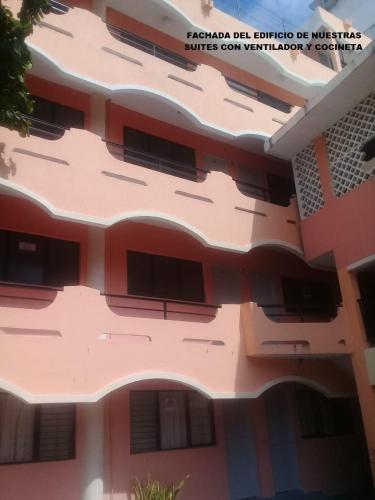 a pink building with a lot of windows at Suites Angelopolis in Acapulco
