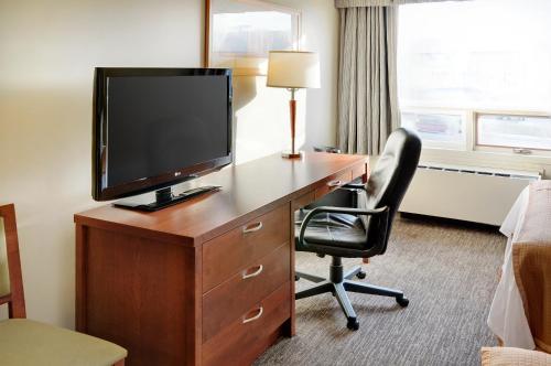 a living room with a desk, chair and television at Quality Inn in North Bay