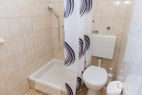 a bathroom with a toilet and a shower curtain at Apartments Lovrić in Vodice