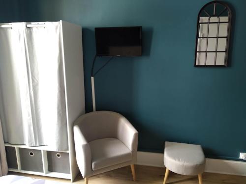uma cadeira e um candeeiro num quarto com uma parede azul em Le Central Vittel 206 em Vittel