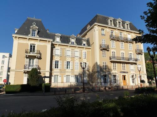 ein großes, braunes Gebäude mit schwarzem Dach in der Unterkunft Le Central Vittel 206 in Vittel