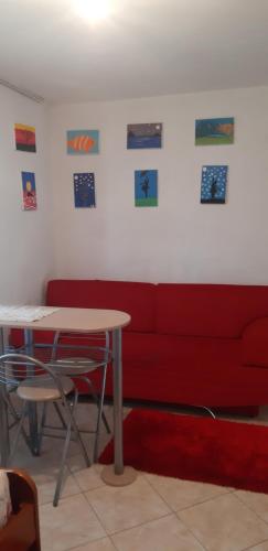 a red couch with a table and some pictures on the wall at Antonio's rooms (2 single beds) in Krujë