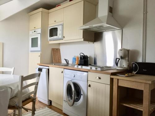 une cuisine avec lave-linge et sèche-linge à côté d'une table dans l'établissement Appartement pour 4 personnes à Fort-Mahon Plage, à Fort-Mahon-Plage