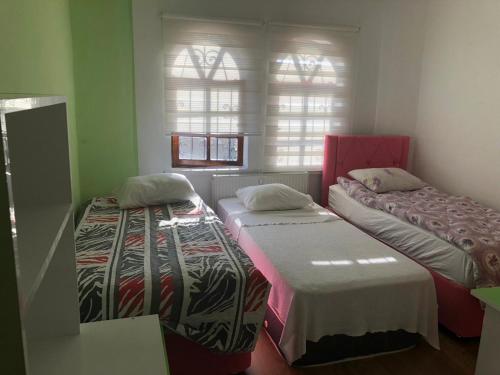 KAPADOKYA REZIDANS في أوروغوب: سريرين في غرفة بها نافذتين