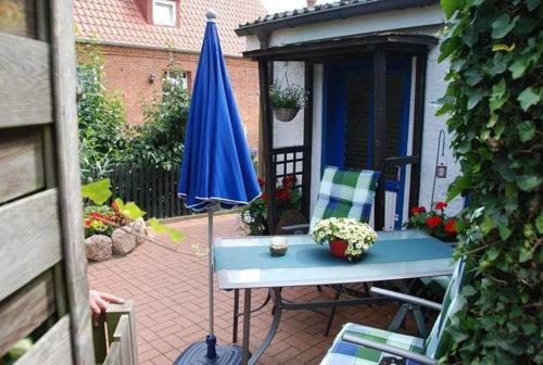 a patio with a blue umbrella and a table and chairs at Schlichte in Kirchdorf