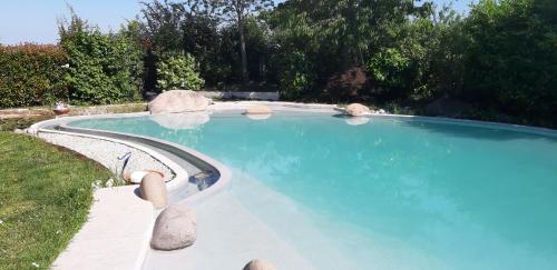 a large swimming pool with blue water in a yard at B&B Torricella in San Giorgio di Piano