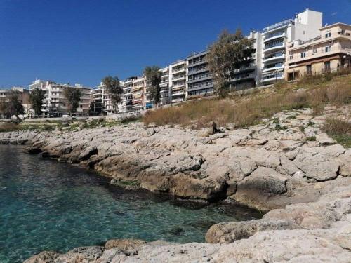a body of water next to some rocks and buildings at LUXURY APARTMENT 6 PEOPLE PORT OF PIRAEUS in Piraeus