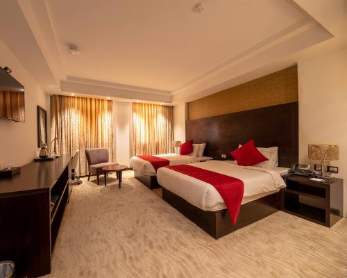 a large hotel room with two beds with red pillows at Horizon Hotel in Al Başrah