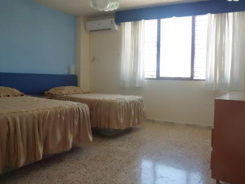 a room with two beds and a window at Suites Angelopolis in Acapulco