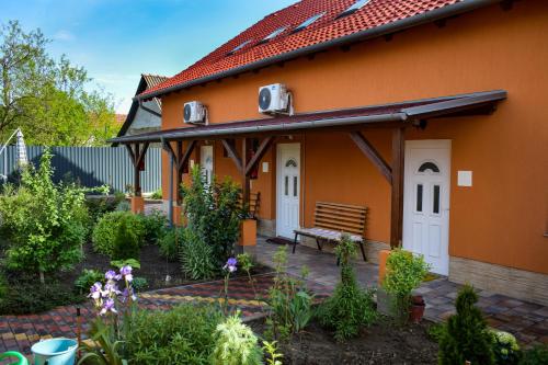 een oranje huis met een bank in een tuin bij LUX Apartman Maroslele in Maroslele