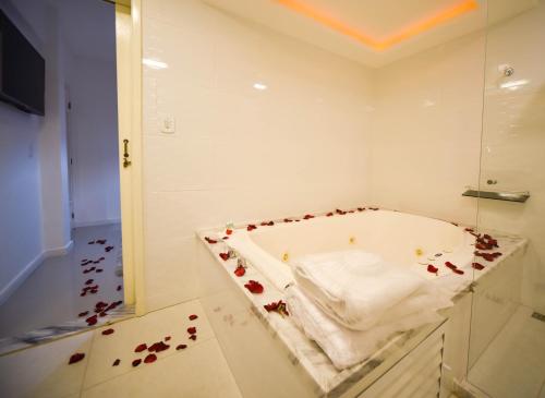 a bathroom with a bath tub covered in rose petals at Pousada de Itaipava in Itaipava