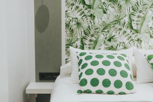 a white bed with a green and white pillow on it at Apartamentos MK77 León - Palomera in León