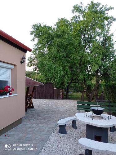 a patio with two benches and a table and a tree at Sárgapart Holiday Home in Poroszló