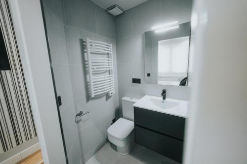 a bathroom with a toilet and a sink and a mirror at Apartamentos MK77 León - Palomera in León