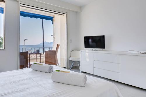 Cette chambre blanche dispose d'une télévision et d'un lit avec deux oreillers. dans l'établissement IMMOGROOM - 3 Sea view Panoramic terrace - 1 min beach - CONGRESSBEACH, à Cannes