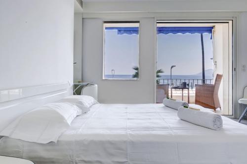 - une chambre blanche avec un grand lit blanc et des fenêtres dans l'établissement IMMOGROOM - 3 Sea view Panoramic terrace - 1 min beach - CONGRESSBEACH, à Cannes