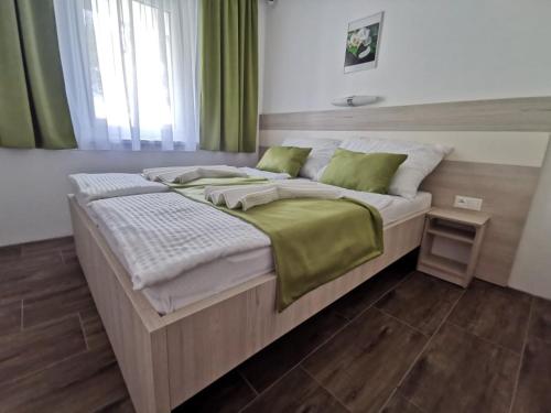 a large bed in a bedroom with green curtains at VILLA MEGER in Veľký Meder