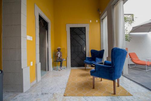 a hallway with blue chairs and a yellow wall at Hotel Casona Independencia in Guadalajara
