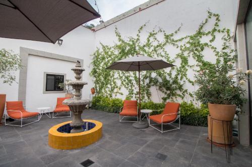 a patio with an umbrella and chairs and a fountain at Hotel Casona Independencia in Guadalajara