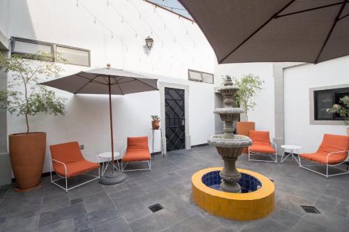 a patio with an umbrella and chairs and a fountain at Hotel Casona Independencia in Guadalajara