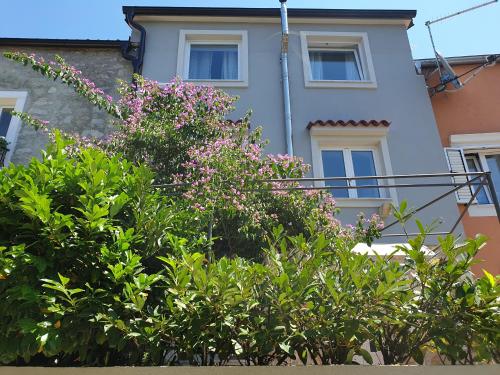 a white house with pink flowers in front of it at Apartment Fay in Mali Lošinj